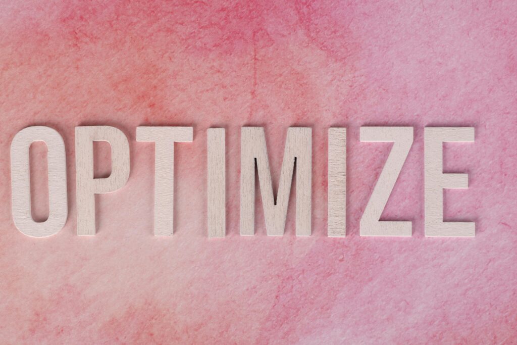 Creative display of the word 'OPTIMIZE' on a pink textured surface.